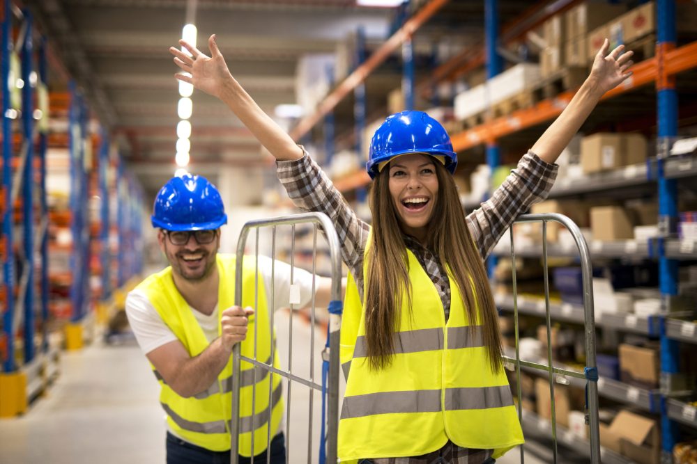 Warehouse workers pushing carts and having fun at work.